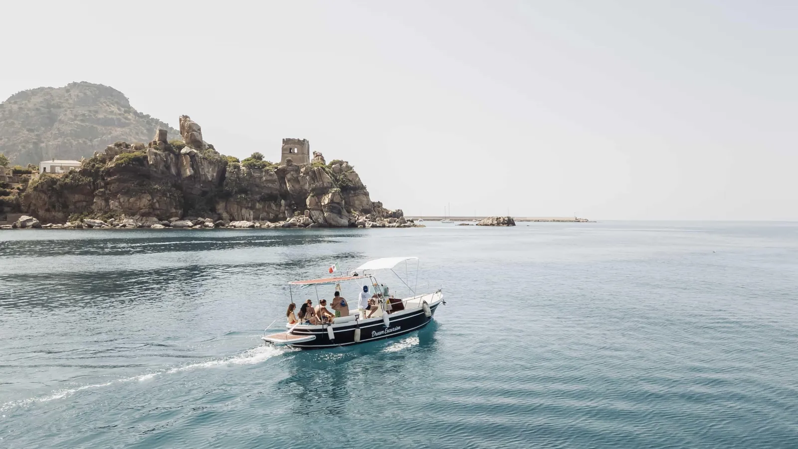 The traditional hull heading back along the coast towards Cefalù with the Rocca in the distance