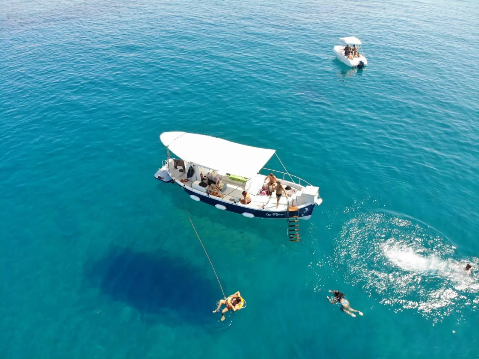 Aerial view of the boat at a swimming stop, guests in the water around it