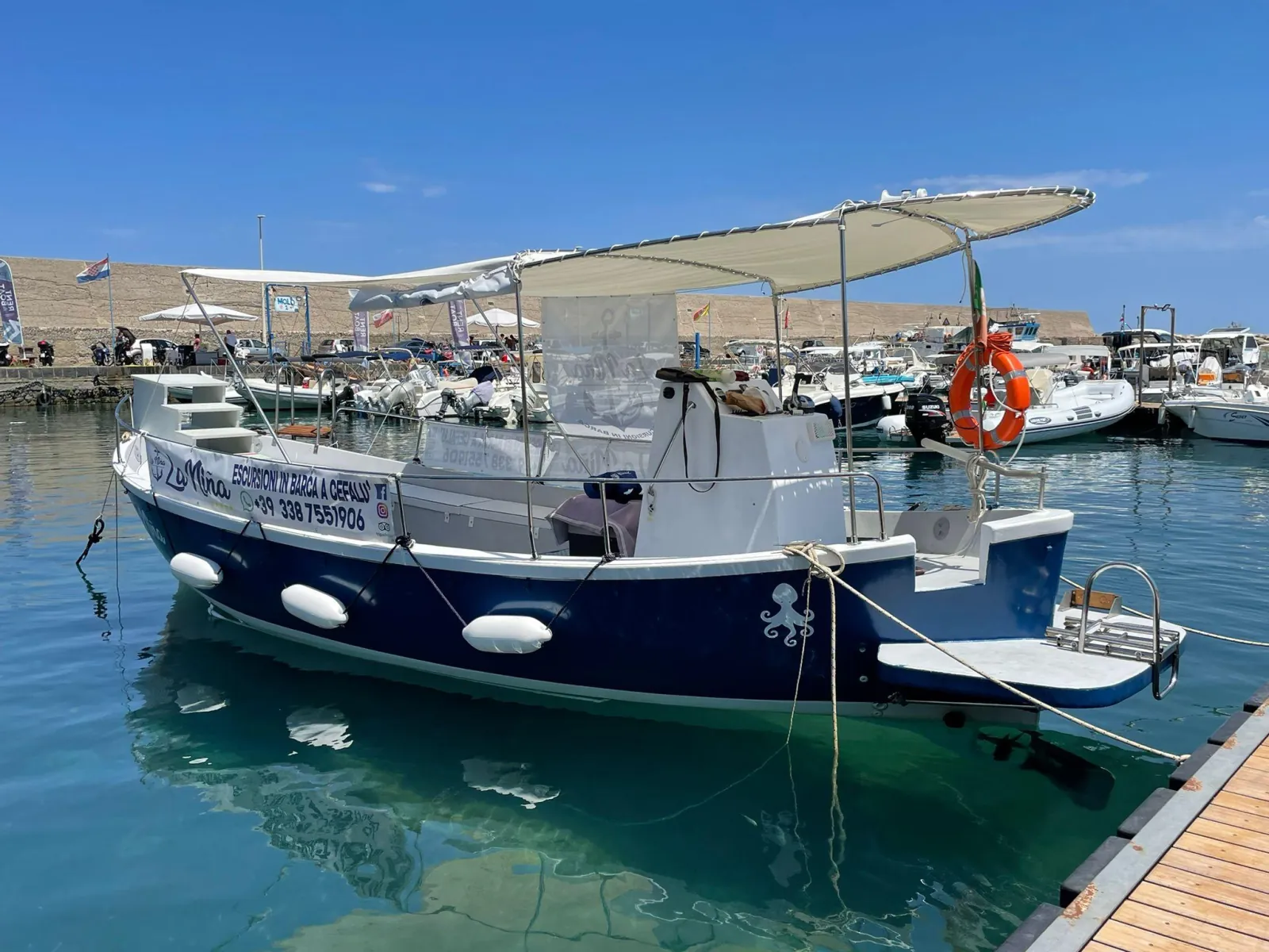 The navy and white excursion boat moored at the quay in Porto Presidiana