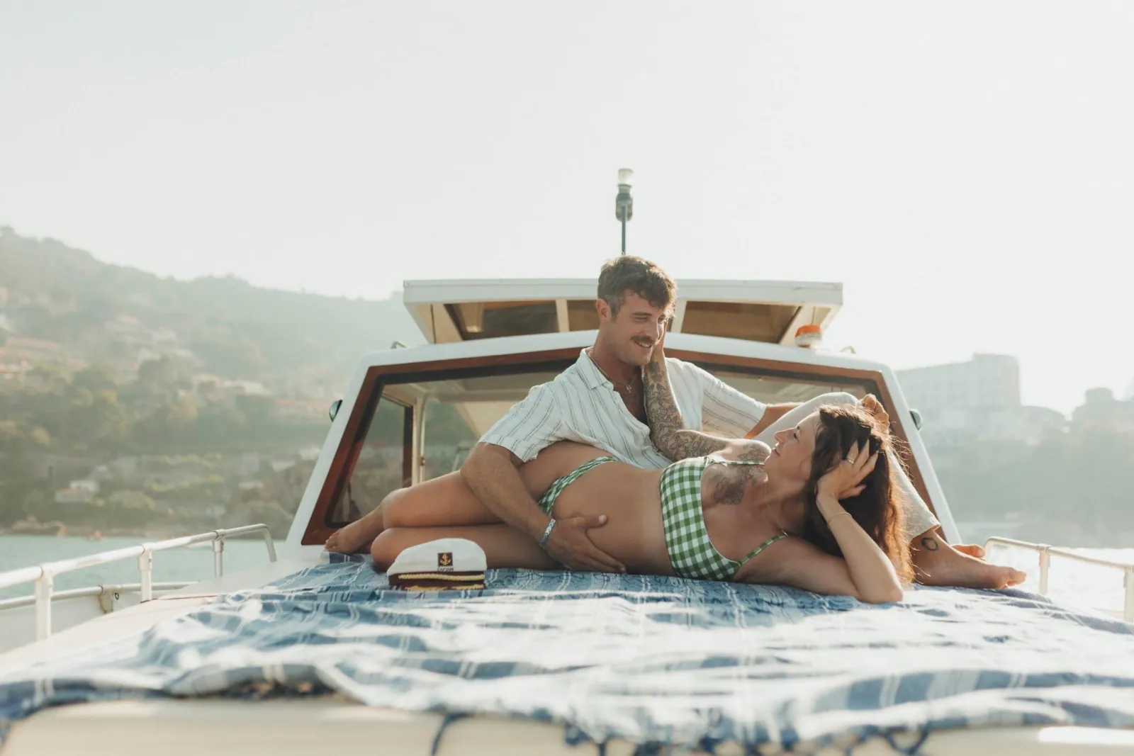 A couple lying on the boat's bow cushions with the open sea ahead