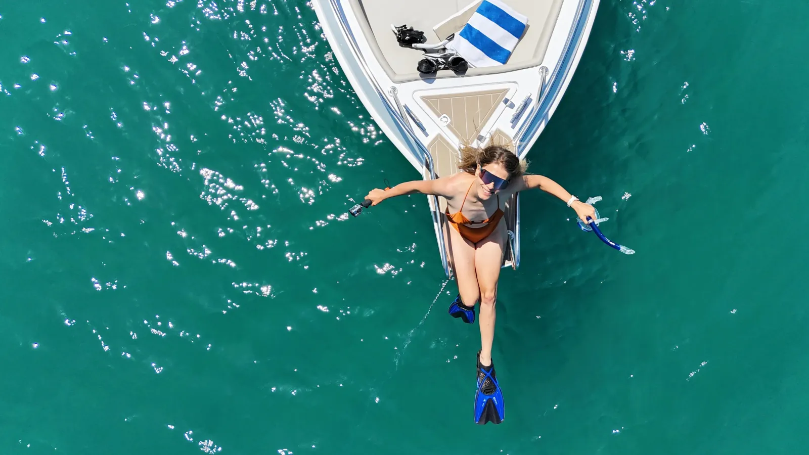 Aerial view of a guest floating in fins beside the boat at a swimming stop