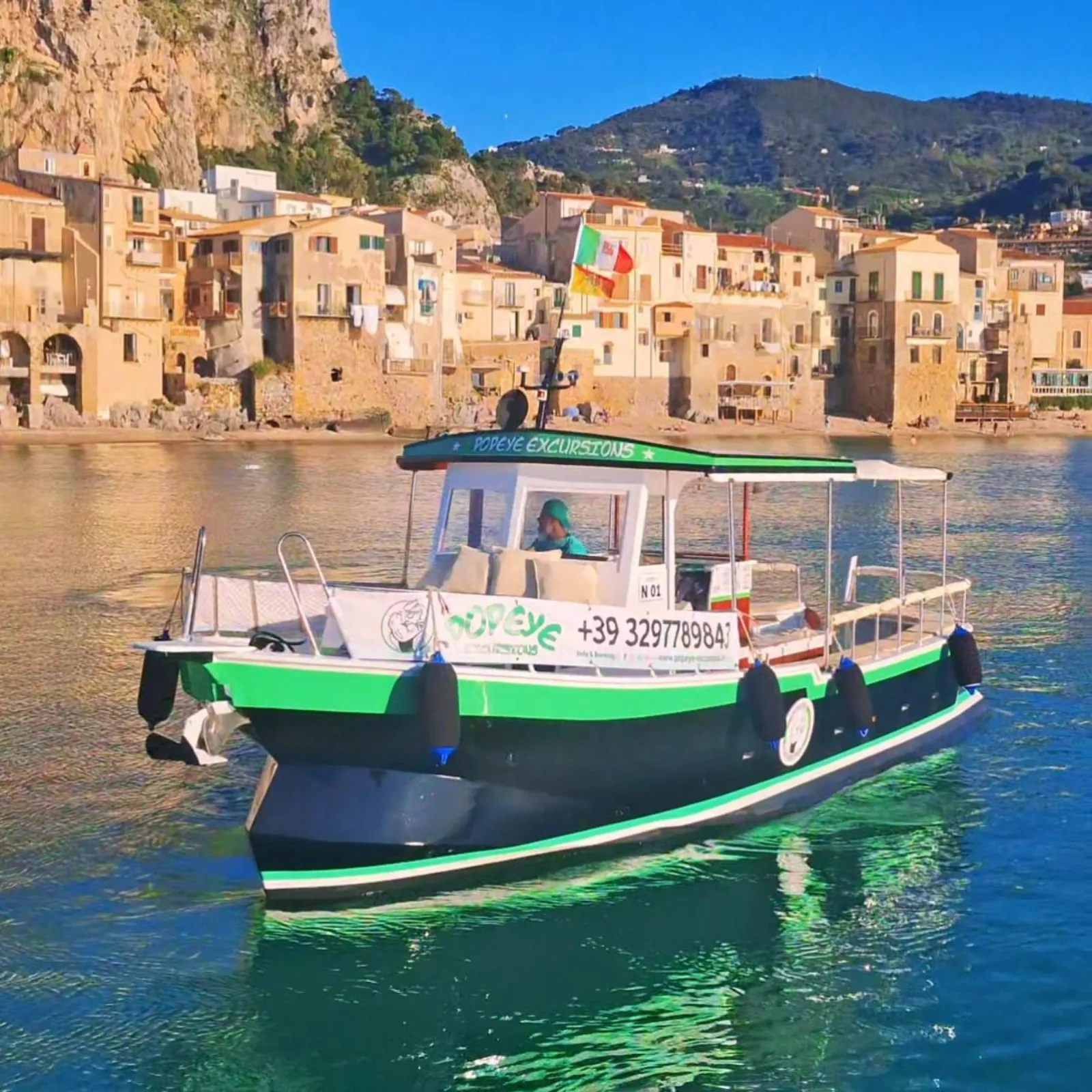 The excursion boat under way in front of Cefalù's waterfront in late-afternoon light